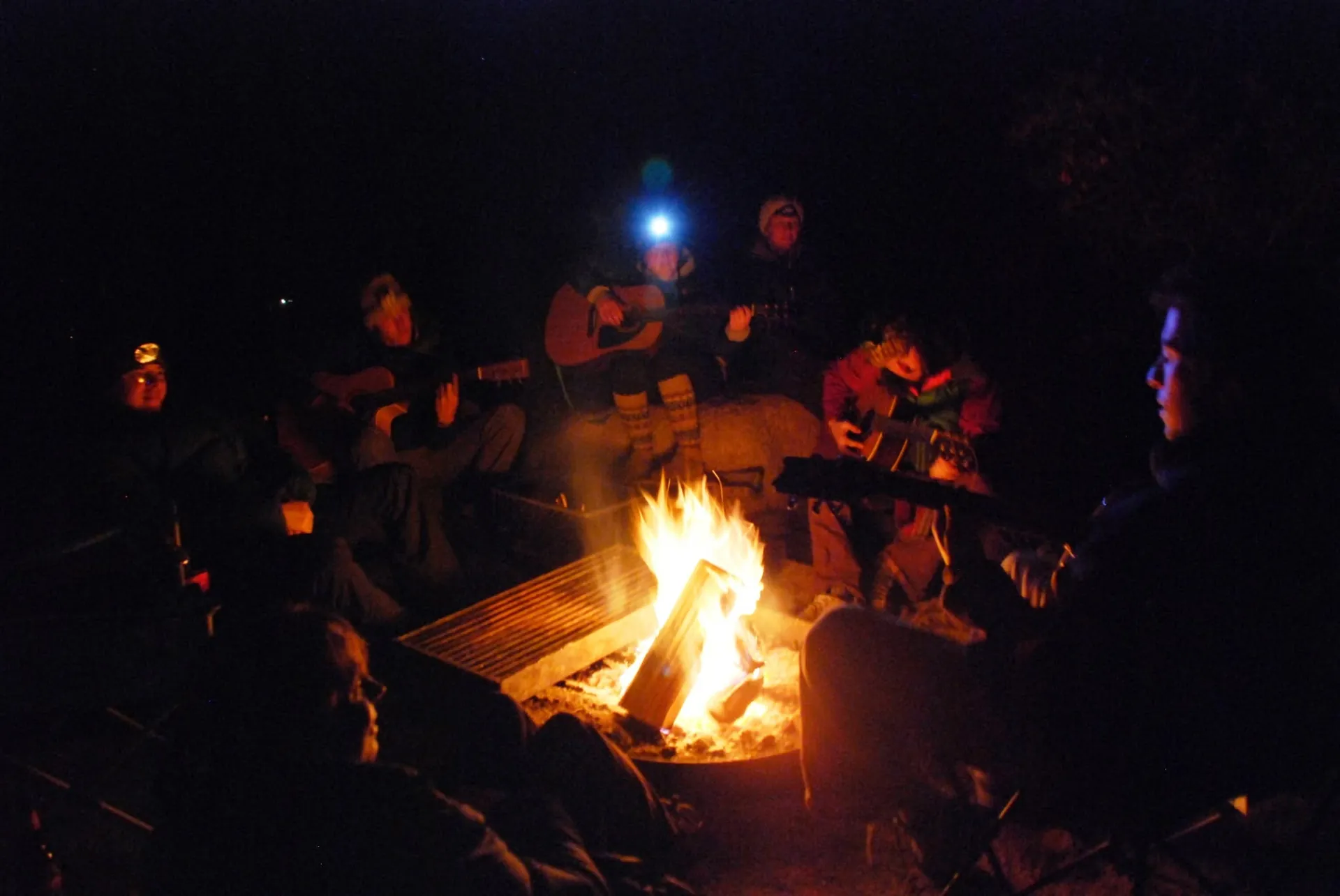 Campers playing guitar around a campfire at River Island RV Park